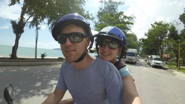 Selfie: Genç Kafkas çift ile bir scooter Asya bir sahil köyü üzerinden gidiyor. Maceracı erkek ve kız arkadaşı muhteşem yaz tatili aşağı güneşli bir yol kıyısına yakın bir motosiklet binmek.