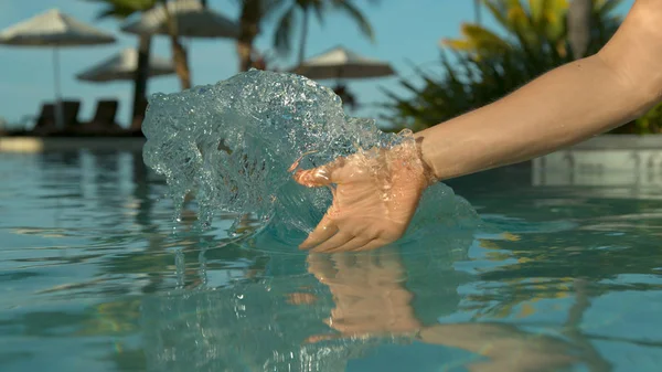 クローズアップ 認識できない女性観光客は 穏やかなプールの水を介して彼女の手をドラッグし 波紋を作成します 白人の女性は フィジー諸島のエキゾチックなホテルリゾートの見事なクリスタルクリアプールで遊ぶ — ストック写真