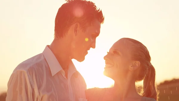 镜头耀斑 湿的女朋友和男友微笑在他们的浪漫的晚上约会在美丽的夏季自然 年轻夫妇站在阳光普照的草地中央拥抱 — 图库照片