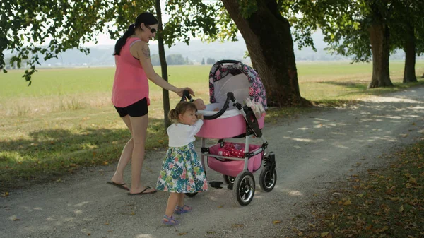 Liten Flicka Som Knuffar Barnvagn Tittar Tillbaka Medan Hon Går — Stockfoto