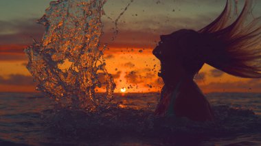 Siluet, Close Up, kopya alanı: muhteşem turuncu günbatımı üzerinde su sıçramasına oynak kadın tatil Cook Adaları. Egzotik gündoğumu ve saçlarını geriye doğru saygısız kız şaşırtıcı görünümü