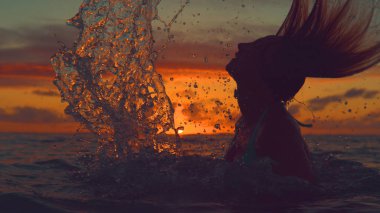 Kadar yakın, siluet: Turuncu yaz gün batımı parlar su saçları ile tanınmaz oynak kız. İnanılmaz güzel bir sabahı denizde serinlemek genç kadın Gezgin görünümünü.