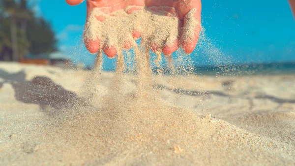 クローズ アップ 楽しい認識できない若い女性休暇 Sifts 柔らかい指先の間粗い砂 女性の手から 日当たりの良いエキゾチックなビーチの上に飛んで白い砂の粒の映画のようなショット — ストック写真