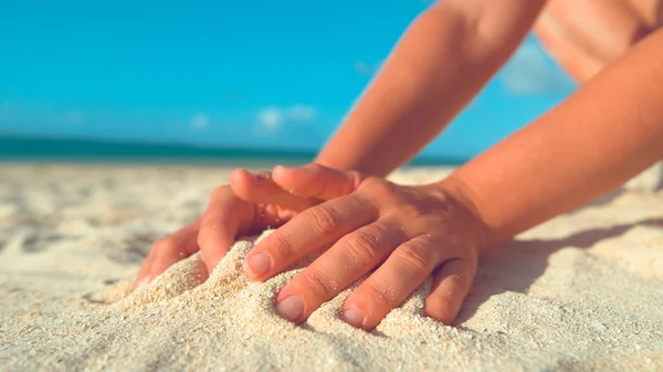 クローズアップ クック諸島のエキゾチックなビーチで遊んでいる認識できない女の子は 空気中にそれを散乱するために砂の山を集めています 彼女の夏休み中に砂の山を形成する未知の女性観光客 — ストック写真