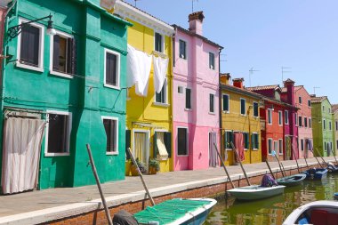 Güzel renkli evler tarafından çevrili bir sakin nehir kanal boyunca yürüyüş. Mavi tekneler güneşli İtalya farklı renkli binaları önünde dinlenme nefes kesen bir kadeh. Ünlü turistik.