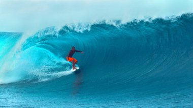 Yakın: Aşırı genç surfboarder muhteşem varil dalga yakınındaki popüler bir sörf Tahiti çarpıcı nokta ile gidiyor. Korkusuz bir pro Erkek sörfçü dev bir derin mavi tüp dalga yakalamak nefes kesen görüntüsünü.