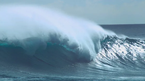 CLOSE UP: Cool shot of emerald ocean wave rolling in summer towards sunny beaches in Chile. Big tube wave glistens in the bright sunshine and sprays refreshing droplets of seawater high in the air.