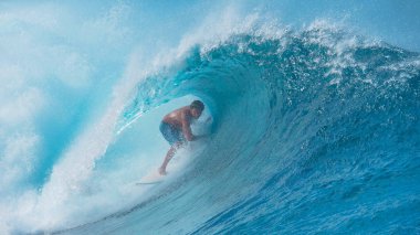 Yakın: Pro surfboarder başının üzerinde curling büyük turkuaz dalga boyunca ellerini sürükler. Fransız Polinezyası ve çılgınca onun arkasında sıçramasına bir tüp dalga sörf surfer dude nefes kesen manzarası.