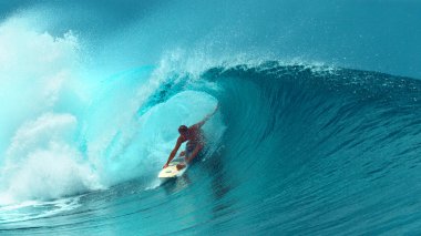 Yakın: Genç profesyonel surfboarder Fransız Polinezyası güneşli bir günde başka bir epik tüp dalga sürme tamamlanır. Eğleniyor ferahlatıcı zümrüt suda sörf için mükemmel bir gün sörfçü.