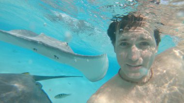 Sualtı, Selfie: eğleniyor mutlu erkek turist dostu stingrays ile kristal berraklığında okyanus su yüzme. Neşeli beyaz adam nazik deniz ışınları ile selfies alarak yaz tatilde.