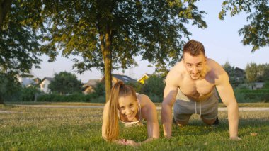 Portre: mutlu atletik kız bir tahta tutar süre gömleksiz uygun erkek gülümseyen bir itme mu. Parkta bir keyifli yaz akşamı birlikte çalışan genç Kafkas çift.