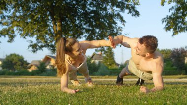 Yakın: sportif çift parkta çalışma dışarı bir tahta ve tarafına dönüm iken yüksek beş tutun. Genç atletik beyaz erkek ve kız arkadaşı tarafından eğitim dışında yaz zevk.