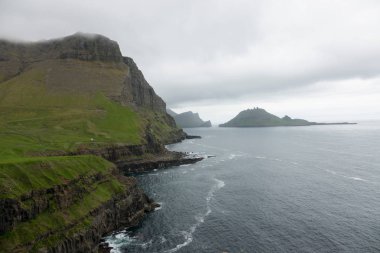 Hava: sakin mavi okyanusa bakan nefes kesici bir çimenli yar boyunca uçan. Faroe Adaları'nın el değmemiş kırsalında dik yeşil peyzaj ve sonsuz deniz çarpıcı çekim.