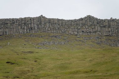 Hava: büyük el değmemiş otlak bakan yüksek bir taş duvara doğru uçan. Muhteşem doğal Faroe Adaları pitoresk kırsalında bir uçurumun doğru giden dik bir yokuş kadeh.