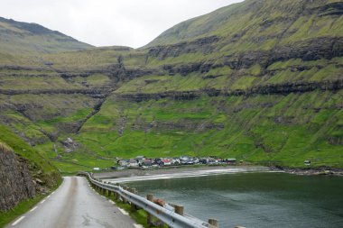Doğal sahil yolu sakin oceanfront köy muhteşem Faroe Adaları'nda yol açar. Çok yüksek çimenli dağlar altında gizli sahil evleri muhteşem manzarası. Çarpıcı İskandinavya yatay