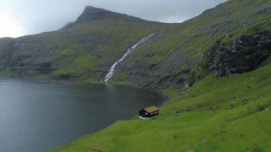 Hava: sakin kırsal waterfront evde doğru çimenli tepeden aşağı uçan. Muhteşem dağ dere kayalık tepeden aşağı ve gölün içine çalışan bir kadeh. Çarpıcı İskandinavya yatay