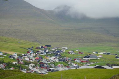 Hava: Faroe Adaları engebeli kırsal renkli bir köyde doğru uçan. Beyaz bulutların üzerinden sarp dağların altında küçük bir kasaba güzel kare çim kaplı. Nefes kesen kırsal manzara.