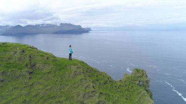Anteni, kopya alanı: Uçan güzel İskandinavya yatay ve geniş deniz gözlem tanınmaz halde kadın fotoğrafçı. Engebeli sahil manzaralı Faroe Adaları'nın muhteşem hava atış.