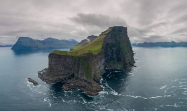 Hava: güzel doğal dağlar ve kayalıklarla ve sakin masmavi deniz manzarası ile küçük çimenli ada etrafında uçan. Adacık güzel İskandinav şehir dışında çarpıcı çekim.