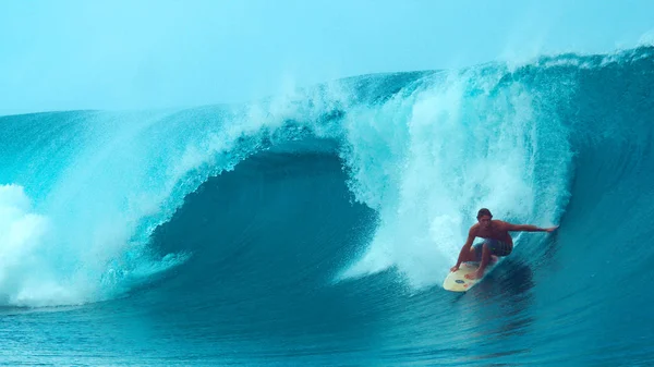 酷冲浪者拖着他的手穿过清爽的海洋 而冲浪一个巨大的桶波崩溃在他身后 令人敬畏的行动拍摄年轻的冲浪者骑完美的管波在塔希提岛 — 图库照片