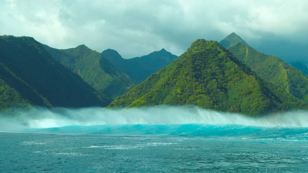 Küçük bir tropik ada Pasifik doğru yağışlı sezon sırasında kabaran dalga büyük tehlikeli okyanus. Turkuaz muhteşem çekim tarafından gür egzotik orman kaplı sakin sahil şeridi yaklaşan şişer.