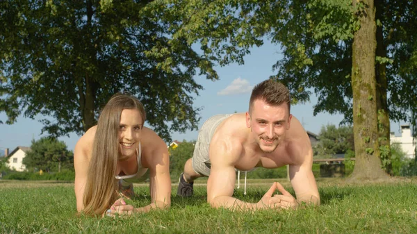 Portre: bir tahta tutarak ve yeşil parkta egzersiz yaparken mutlu atletik çift gülümsüyor. Gömleksiz erkek ve güzel kız arkadaşı birlikte doğa sıcak yaz havalarda iş dışarı.