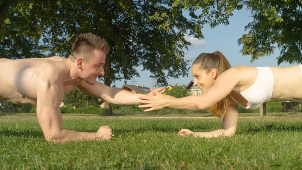 Yakın: atletik çift yüksek beşli gülümseyen güneşli parkta egzersiz yaparken. Neşeli gömleksiz adam ve uygun kadın ise bir tahta holding ve doğada çalışma dışarı çırp. Mutlu eğitim ortakları.