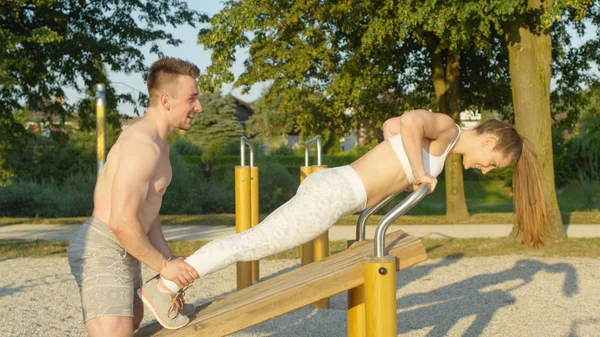 Nahaufnahme Muskeltrainer Hält Frau Den Knöcheln Während Sie Liegestütze Parkturngeräten — Stockfoto