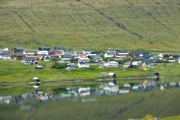 在一个安静的小村庄里 可以看到河滨房屋的风景如画的景色 以及它们在水中的倒影 令人叹为观止的镜头崎岖的乡村和沿海小镇在壮观的法罗群岛 — 图库照片