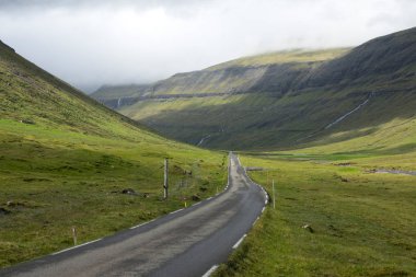 Hava: Faroe Adaları'nda güzellikteki bir vadinin üzerinden çalışan bir boş asfalt yol boyunca uçan. Sarp çimenli tepeler ve engebeli İskandinav şehir dışında somut bir iz sinematik görünümünü.