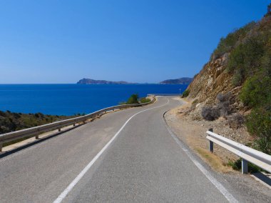 Boş asfalt yol rüzgar gün güneşli yaz nefes kesen Sardunya'nın doğal kıyı şeridi boyunca. Sahil yolu açık mavi gökyüzü ve sakin Akdeniz manzaralı muhteşem çekim.