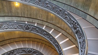 CLOSE UP: Beautiful ornate spiral staircase winding down the empty historic museum. Cool shot of the famous Bramante stairwell in Vatican city. Breathtaking decorated steps illuminated by lights. clipart