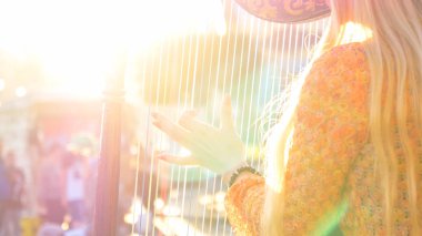 Close Up, Lens Flare: Güneşli bir günde Roma'nın güzel sokaklarında arp çalan tanınmayan kadın sokak sanatçısı. Açık havada performans gösteren sarı saçlı bilinmeyen bir bayan Sinematik görünümü.