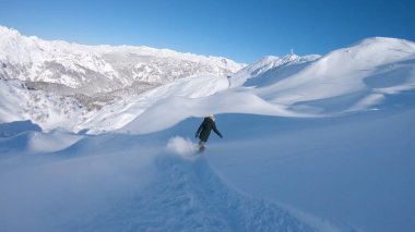 Havalı bir kadın yeni yağmış karla kaplı bir dağdan snowboard 'uyla iniyor. Nefes kesen Alplerde aşırı derecede kadın snowboardcu eğleniyor. Taze toz kar oyan bir kızın sinematik çekimi.