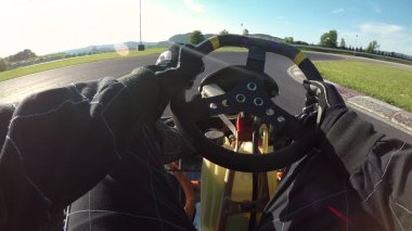 POV, Lens Flare: güneşli bir günde bir engebeli asfalt yarış pisti boyunca kart gitmek yarış eğleniyor. Kol ve bacak raceway çevresinde hızlı bir go-kart cool zaman deneme yarışma sırasında sürüş güzel kare.