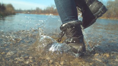 Kadar yakın, düşük açı: Oynak kadın güzel saf sığ nehir boyunca çalışan tüylü çizmeli. Bilinmeyen kız güzel sonbahar gününde ayakları ile camsı Göl su sıçramasına sinema çekim.