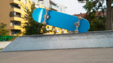 Kadar yakın, düşük açı: Genç erkek kaykaycı paten parkta güneşli bir günde varial kickflip inecek. Onun mavi kaykay ile serin bir fiske vurmak hile yaparak tanınmaz halde bir erkek atlet görüntüsünü kapatmak.