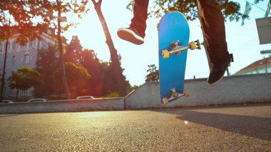 Close Up, düşük açılı Lens Flare: tanınmayan adam güneşli şehirde kaykay havada iki yıl boyunca parmak mavi pano çevirir. At binme ve güneşli sonbaharda yapan kaykaycı güzel kare.