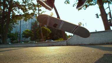 Düşük Açı, Close Up: Tanınmayan patenci güneşli şehir sokaklarında sürüş sırasında serin bir flip yok. Genç adam paten ve güzel sonbahar gününde conrete paten parkta hileler yapıyor.