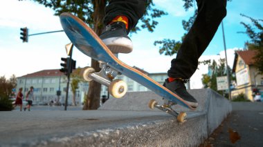 CLOSE UP DOF: Young skateboarder tail grinds a concrete ledge in skatepark. Unrecognizable skater dude wearing cannabis socks doing cool tricks on his skateboard on a beautiful autumn day in the city.