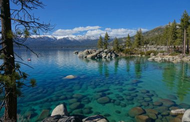 Breathtaking view of the snowy mountains overlooking the emerald colored lake in the scenic American wilderness. Warm autumn sun shines on the idyllic national park in USA. Spectacular Tahoe Lake.