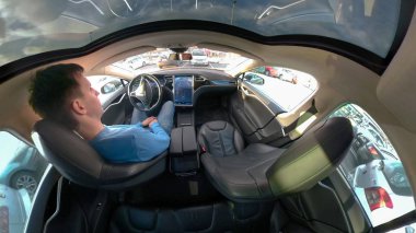 Tesla özerk araba, Mart 2018 - kadar yakın: otonom araç kendi kendine park eder iken erkek sürücü konforlu deri koltuğunda hala oturuyor. Kaygısız adam serin bir öz Tesla arabayı park sürüş.