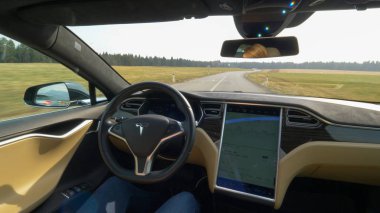 Tesla özerk araba, Mart 2018 - Pov: Genç kadın kendini bir direksiyon Tesla araba bir boş ülkede yol aşağı yolculukları. Güneşli kırsal manzara yolda sürüş otonom araç çevreleyen.