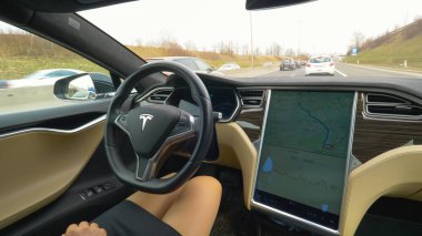 Özerk Tesla arabayı, Mart 2018 - yakın: bitirim kendini direksiyon araca sırasında çalışmaya commuting tanınmaz halde genç bir kadın. Bilinmeyen işkadını bir yüksek teknoloji araba otoyol aşağı seyir.