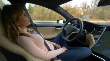 Özerk Tesla araba, Mart 2018 - kadar yakın: sıkı arabasını Uyuyan Genç kadın onu aşağı karayolu ve onun hedef için kullanıyor. Hız kendini direksiyon arabada uyuklayan yorgun kadın turist. Yorgun gezgin kız şekerleme alır