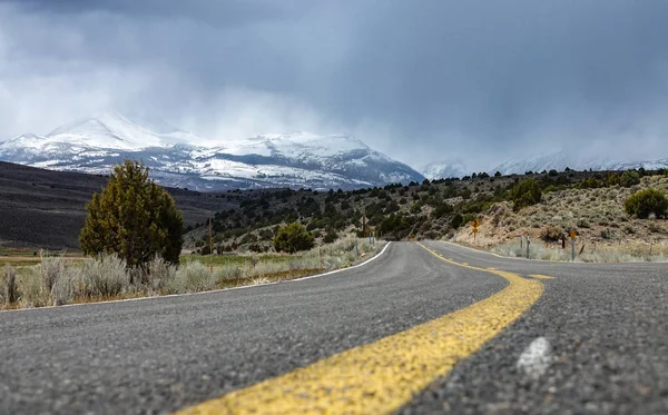 Baixa Ângulo Estrada Asfalto Vazia Que Leva Direção Montanhas Nevadas — Fotografia de Stock