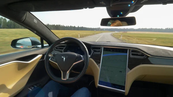 Tesla özerk araba, Mart 2018 - Pov: Genç kadın kendini bir direksiyon Tesla araba bir boş ülkede yol aşağı yolculukları. Güneşli kırsal manzara yolda sürüş otonom araç çevreleyen.