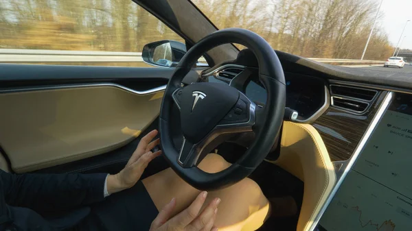 Özerk Tesla araba, Mart 2018 - kadar yakın: İyi giyimli kadın elleri otobanda araba hız sürüş kendini ayarlamak için kaldırıncaya. Otomobil direksiyon simidi kapma ürküyor kadın olduğunu düşünüyor 