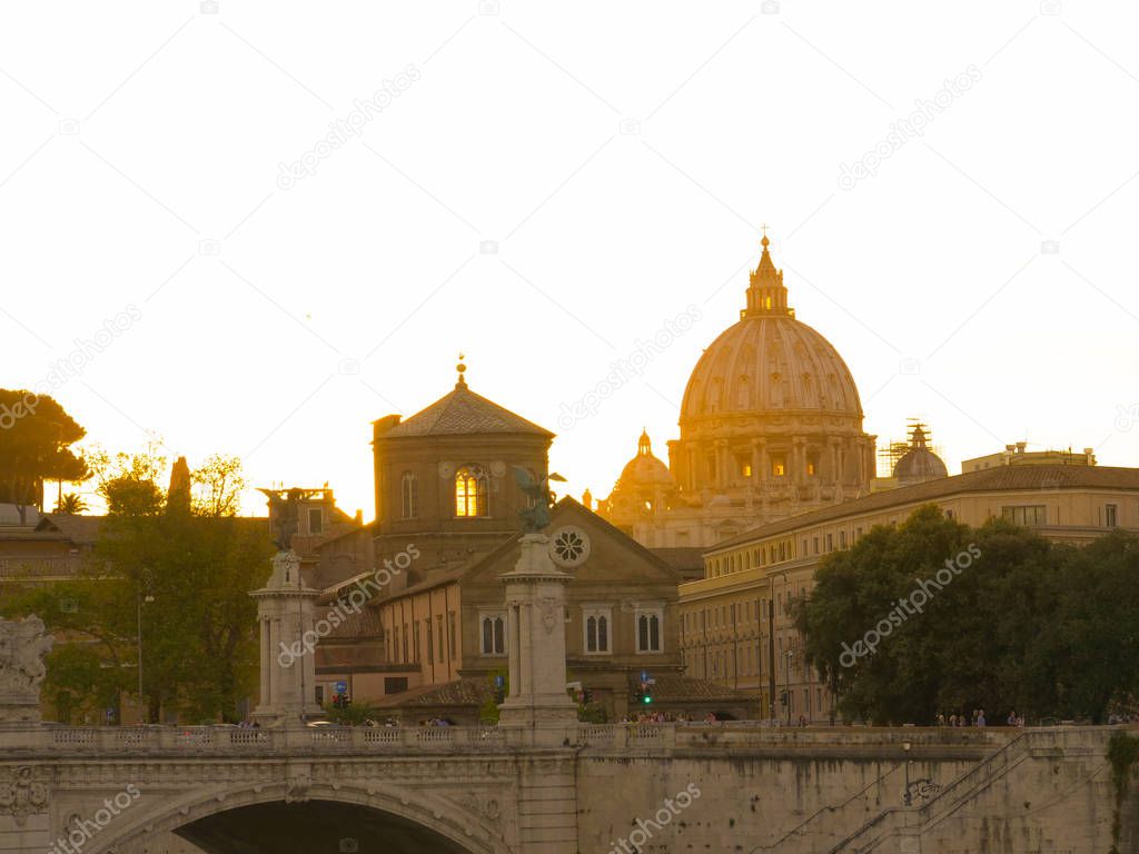 Golden evening sun rays illuminate the historic Sistine chapel in Vatican City. Breathtaking St. Peter's basilica on a picturesque summer morning. Countless travelers on sightseeing trip of old Rome.
