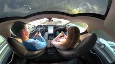 Tesla özerk arabayı, Mart 2018 - yakın: dikkatsiz genç çift manifatura serin Tesla robot arabayla sürüş sırasında. Pervasız erkek ve kadın otoyol seyir ederken onların akıllı telefonlar ile işe yaramaz.
